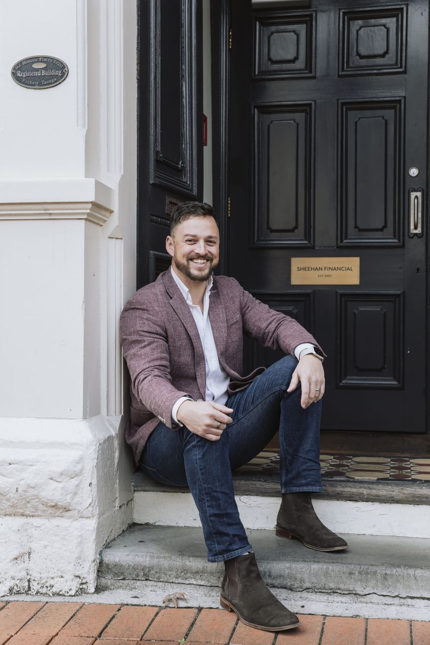Sam Squire, Financial Adviser at Sheehan Financial, sitting on the office front steps